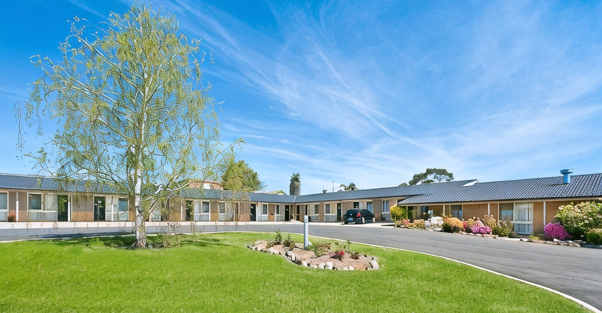 Bega Village Motor Inn seen across its lawns and flower beds on a clear day