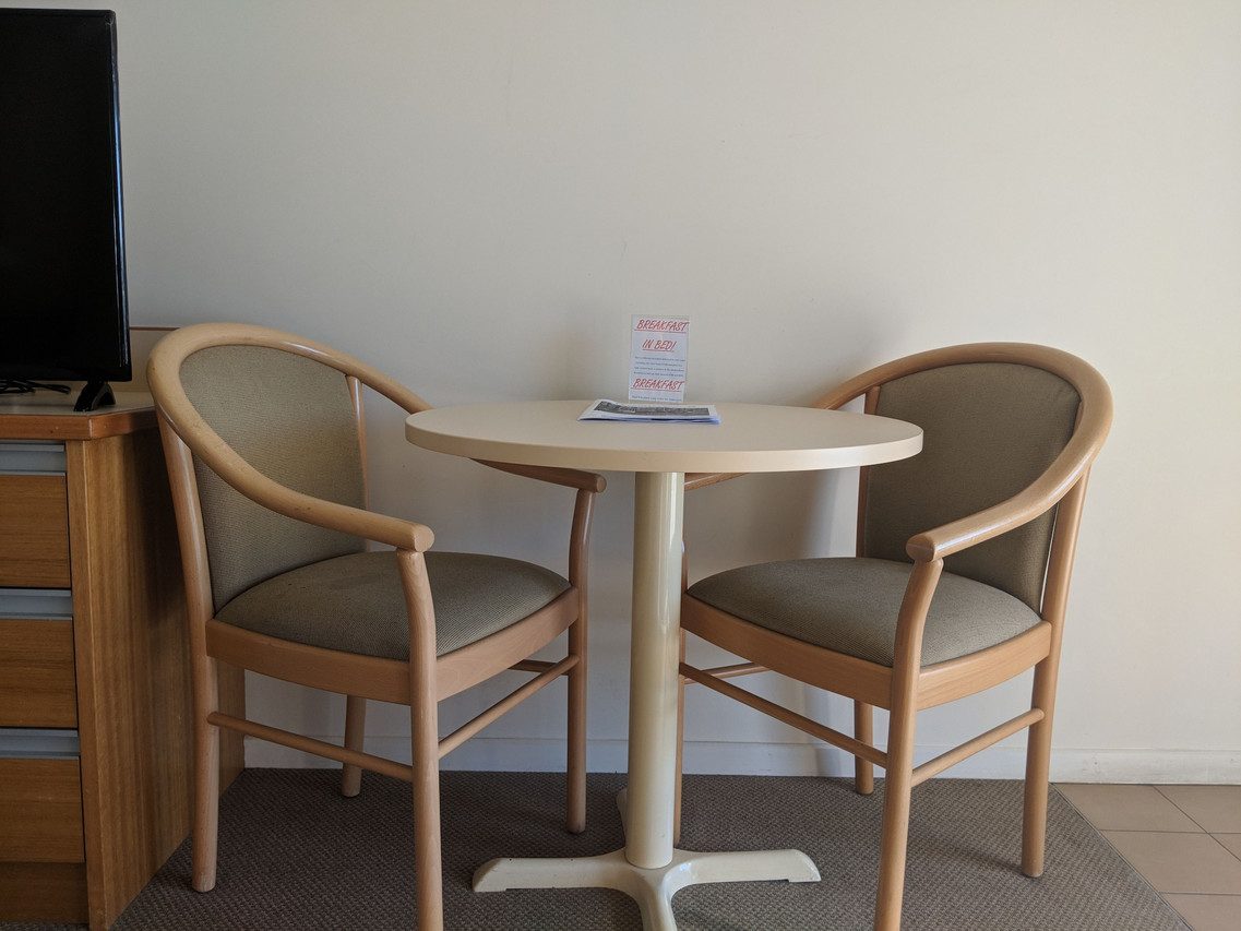 Accessible room interior with a round dining table, two chairs and a flat-screen television