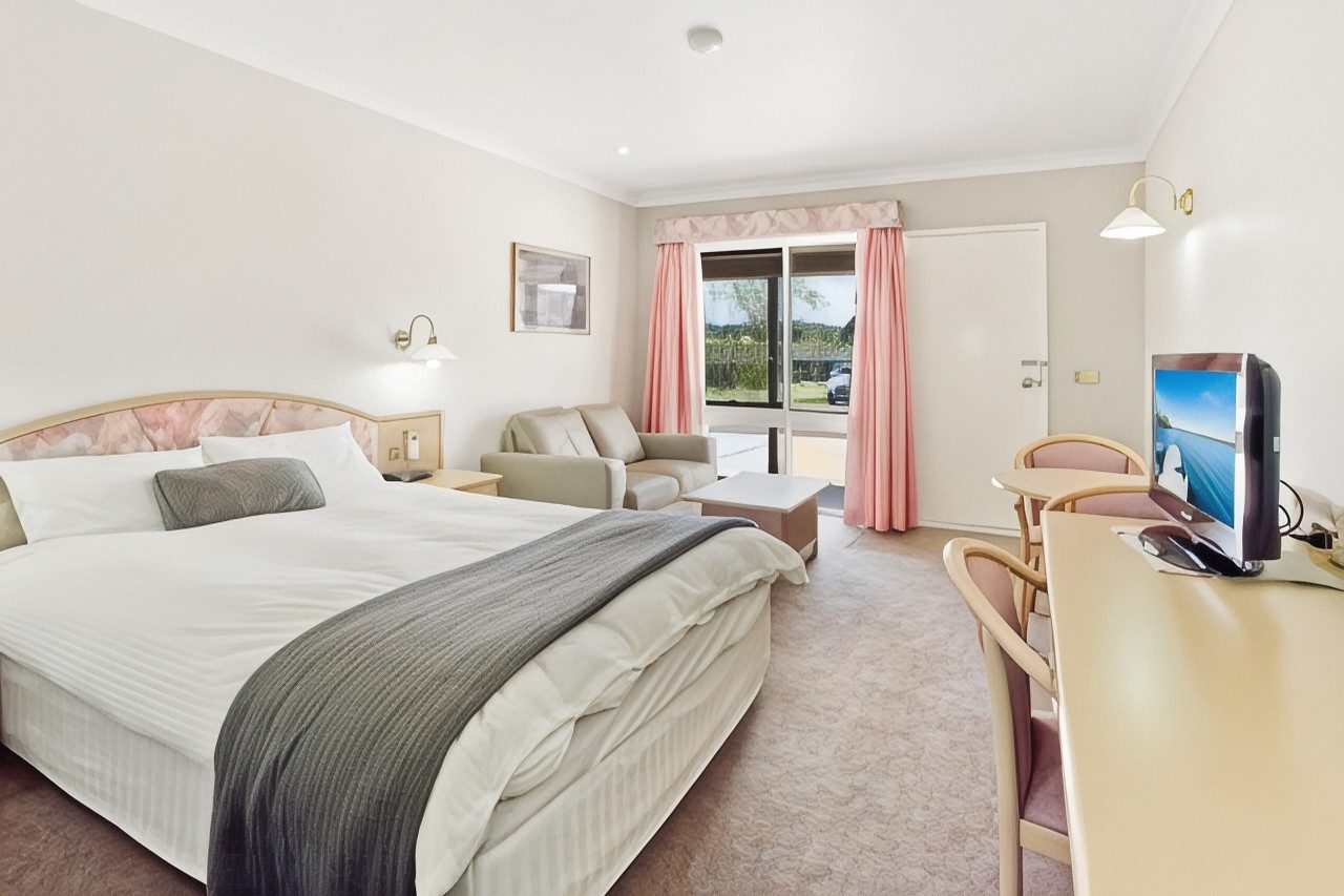 Executive Queen Room with a queen bed, bedside lamps and a comfortable sofa
