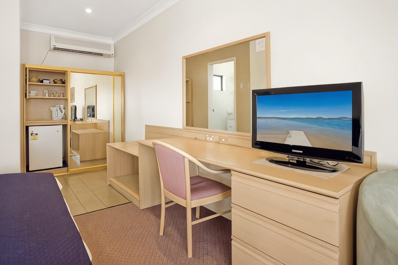 Family room showing the kitchenette bench, refrigerator, mirror and flat-screen television