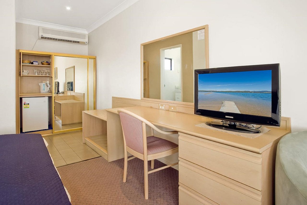 Villa interior showing the kitchenette console with refrigerator, bench and television