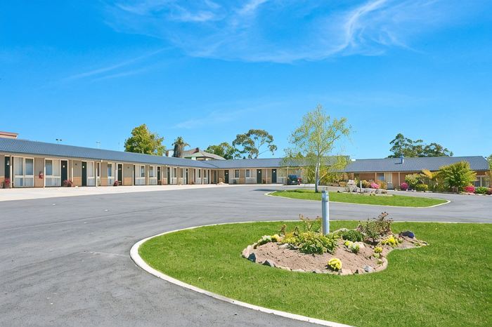 The motel's ground-floor wing and driveway with a circular garden bed in the foreground