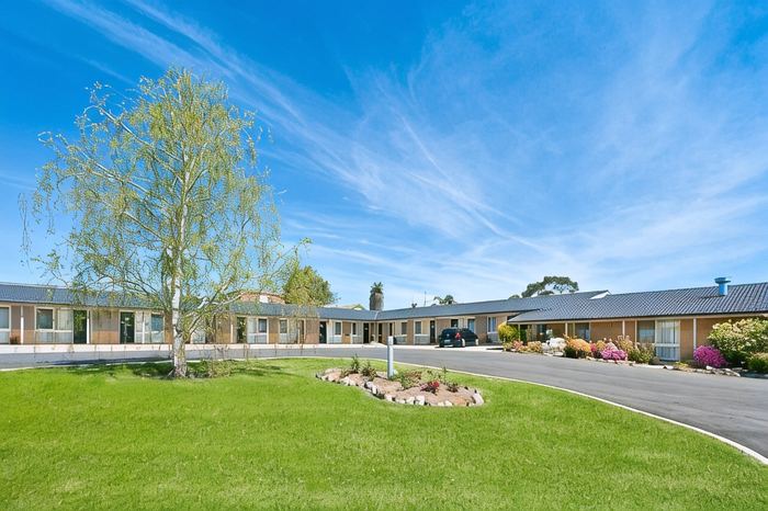 The motel wings viewed across wide lawns and flower beds under a clear sky