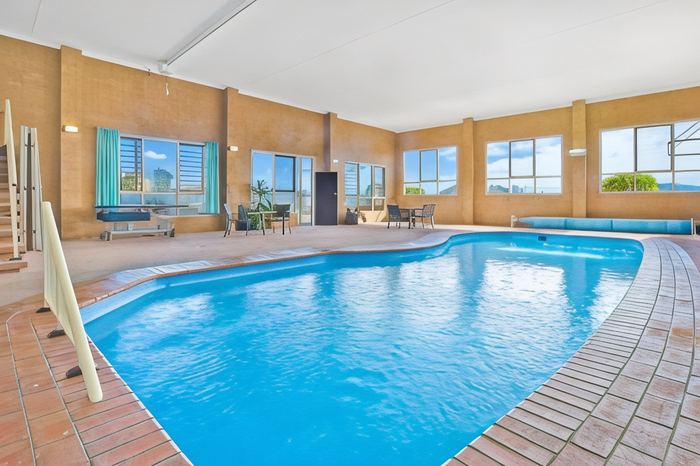 The indoor heated swimming pool with poolside seating and windows along one wall