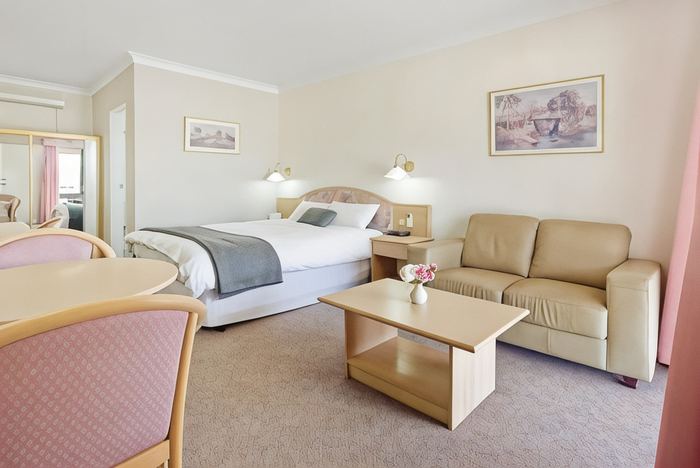 Two Room Suite with queen bed, leather sofa, coffee table and dining table with chairs